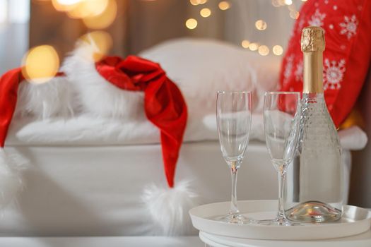 Two glasses and a bottle of champagne in a hotel room with Christmas decor. The concept of celebrating the new year in travel and hotel.