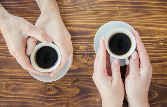 Cups with a coffee in the hands of men and women.