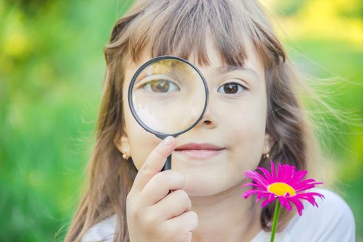 The child is looking in a magnifying glass. Increase. selective focus.