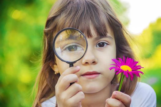 The child is looking in a magnifying glass. Increase. selective focus.