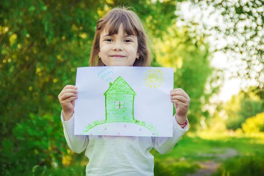 Drawing of a green house in the hands of a child.