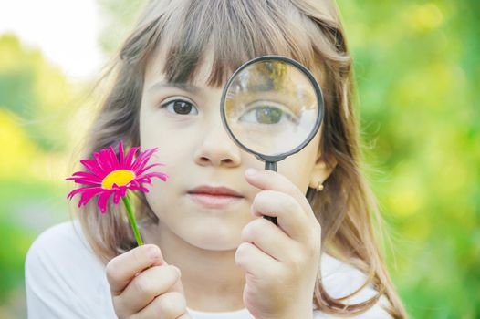 The child is looking in a magnifying glass. Increase. selective focus.