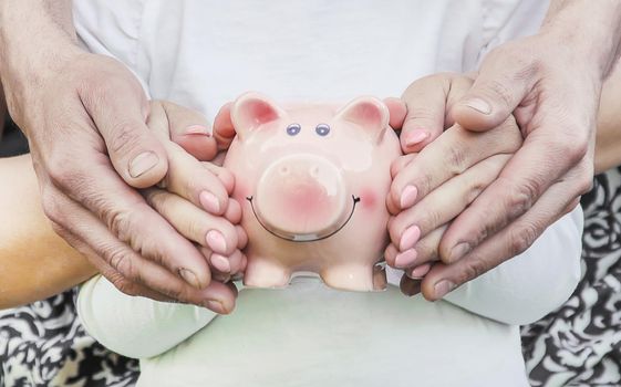 The child and parents are holding a piggy bank in their hands. nature.