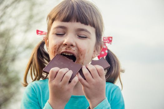 A sweet-toothed child eats chocolate. Selective focus.