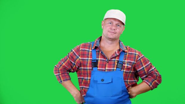 smiling male farmer in plaid shirt and hat holds beautiful sweet pepper,playing, throws it, on Chromakey, green background. concept of Healthy food to your table. High quality photo