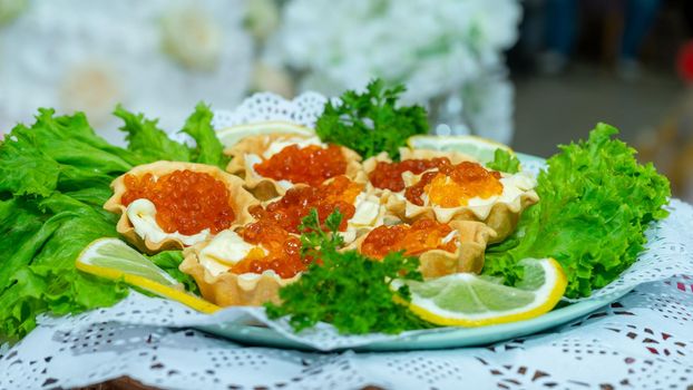 Red caviar and grated cheese in small dough baskets. A delicious cold appetizer with seafood.