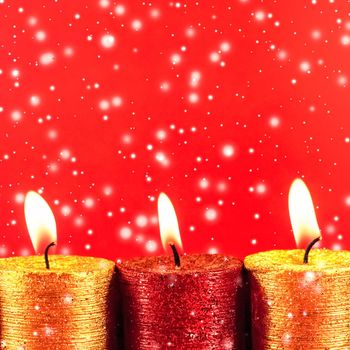 Winter, celebration and new years eve concept - Christmas candles and shiny snow on red background, holiday season decoration