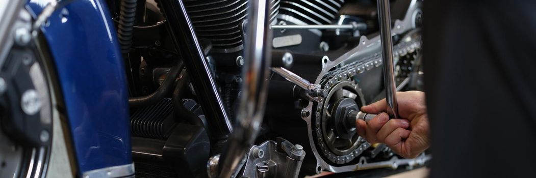 Close-up of professional mechanic fixing part of motorbike transport with wrench instrument. Pit stop for vehicle to get help. Maintenance service concept