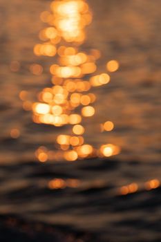 Awe beautiful vibrant orange shallow sun path of round highlights spot particles on sea out of focus area. Summer travel scene