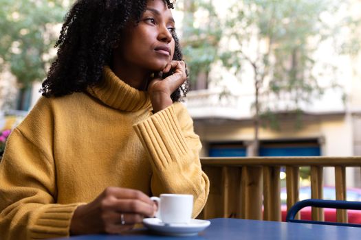 Pensive Young African American woman having espresso coffee in a cafe terrace in the city. Copy space. Lifestyle concept.