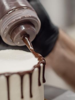 unrecognizable worker preparing a sweet dripping choco cake and berries