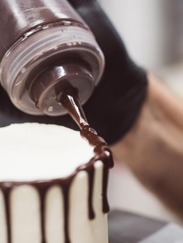 unrecognizable worker preparing a sweet dripping choco cake and berries