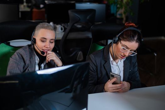 Two women in protective masks are bored at work. Call center operators at the desk.