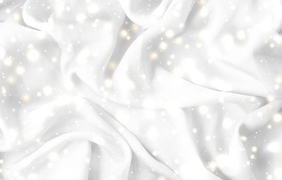 Winter fashion, shiny fabric and glamour style concept - Magic holiday white soft silk flatlay background texture with glowing snow, luxury beauty abstract backdrop