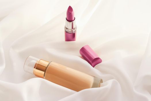 Cosmetic branding, glamour and skincare concept - Beige tonal cream bottle make-up fluid foundation base and pink lipstick on silk background, cosmetics products as luxury beauty brand holiday design