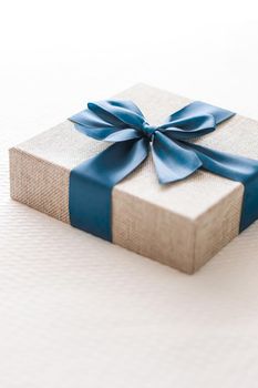 Holiday present and luxury online shopping delivery, wrapped linen gift box with blue ribbon on bed in bedroom, chic countryside style, close-up