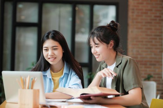 Two Young woman studying for a test or an exam. Tutor books with friends. Young students campus helps friend catching up and learning.