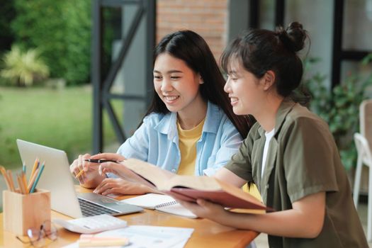 Two Young woman studying for a test or an exam. Tutor books with friends. Young students campus helps friend catching up and learning.