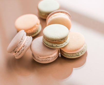 Pastry, bakery and branding concept - French macaroons on cream beige background, parisian chic cafe dessert, sweet food and cake macaron for luxury confectionery brand, holiday backdrop design