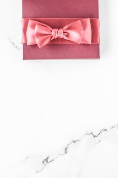 Birthday, wedding and girly branding concept - Coral gift box with silk bow on marble background, girl baby shower present and glamour fashion gift for luxury beauty brand, holiday flatlay art design