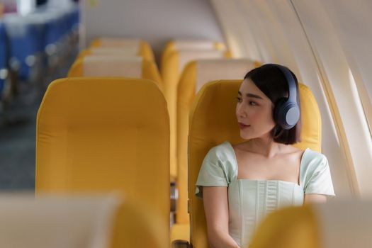 Young asian woman using smartphone connected to wifi internet during flight on board. Travel concept.