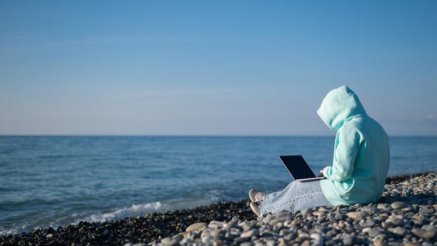 Caucasian woman working freelance on laptop on the beach