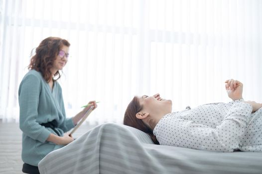 A middle-aged woman lies on a couch and talks to a psychologist