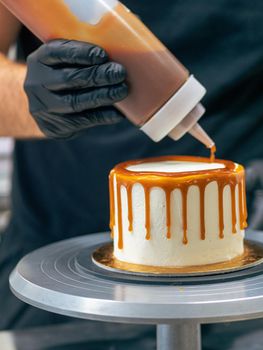 professional baker decorating a chocolate and cream cake with salty caramel