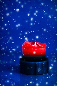 Happy holidays, greeting card and winter season concept - Red holiday candle on blue sparkling snowing background, luxury branding design for Christmas, New Years Eve and Valentines Day