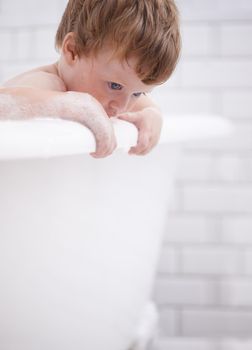 Getting fresh and clean. Tiny red-headed toddler in the bath tub