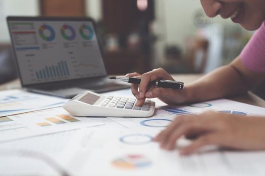 Business woman hand using calculator to calculate the company's financial results and budget. Account Audit Concept.