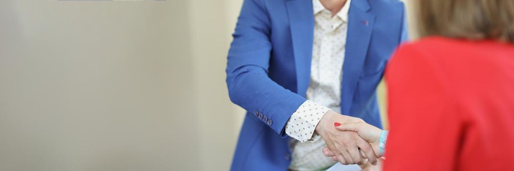 Portrait of handsome young man greeting woman with handshake dressed in trendy suit. Business meeting to sign up contract. Deal, agreement, success concept