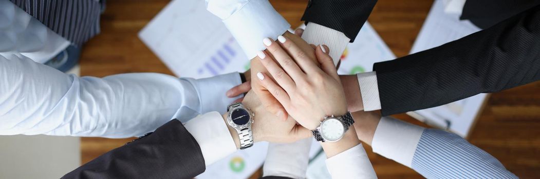 Top view of colleagues performing gesture in order to prepare for important profitable project, change future of corporation. Teamwork, business concept