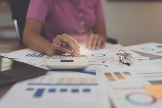 Asian Businesswoman calculating saving account balance with calculator, account and saving concept.