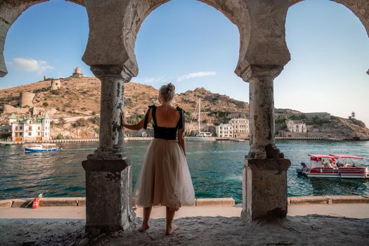 Side view portrait of a relaxed woman breathing fresh air at the seaside. She stands near the old column