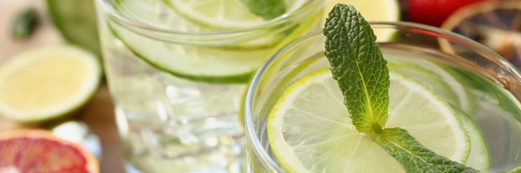 Close-up of cooling drinks cocktails in glasses on table, lime with lemon and mint, cheers or toast. Summer fruit beverages for company. Party, fun concept