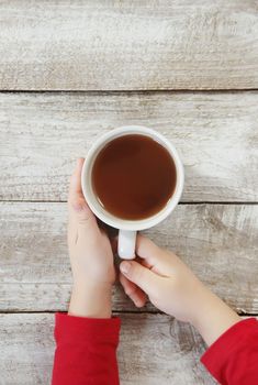 A cup of tea in the hands of a child. Comfort.