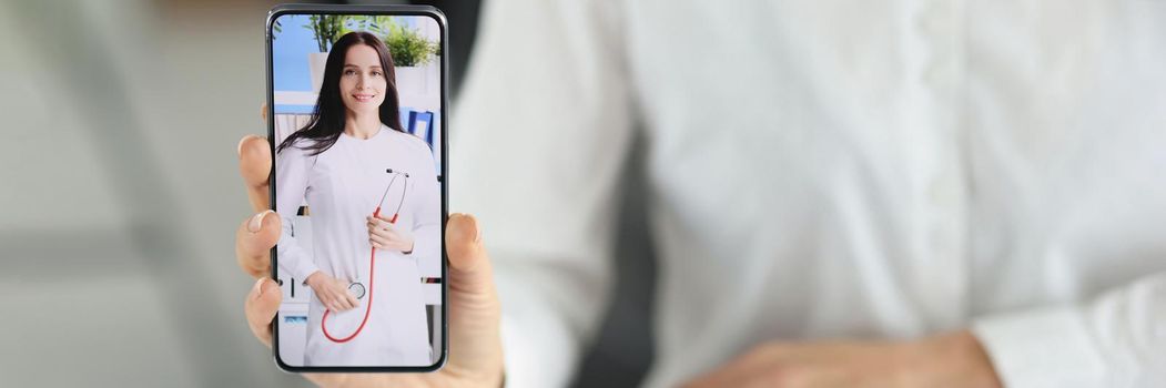 Close-up of woman office worker show smartphone with doctor woman on screen, change qualification. Brave enough to change profession. Retraining concept