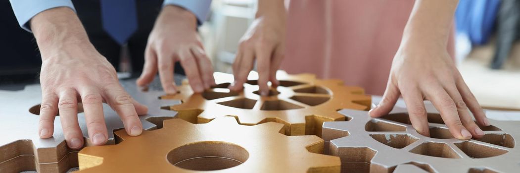 Close-up of businesspeople put wooden gears on workplace together, work in team. Teamwork, cooperation, successful development, game, erudition concept