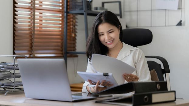 Asian Businesswoman smiling and working to analyze technical price graph and indicator. finance concept.