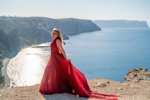 A woman in a red flying dress fluttering in the wind, against the backdrop of the sea