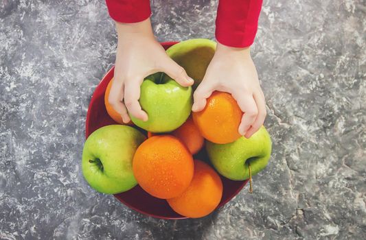 apples and oranges in the hands of a child.