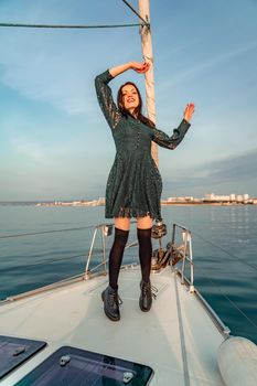 Woman standing on the nose of the yacht at a sunny summer day, breeze developing hair, beautiful sea on background.