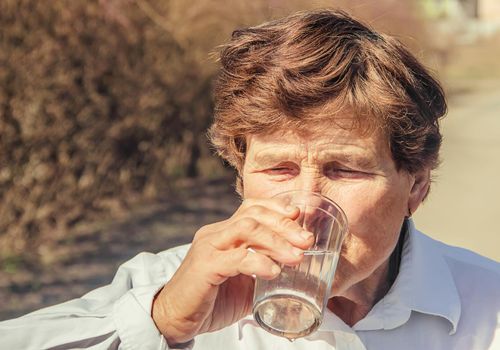 Grandmother giving a glass of clean water to a child. Selective focus.
