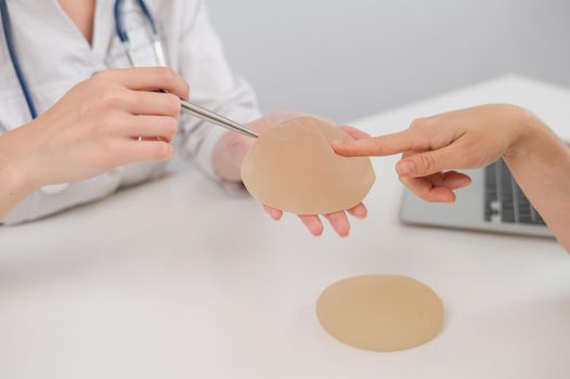 Caucasian woman and plastic surgeon choosing breast implants