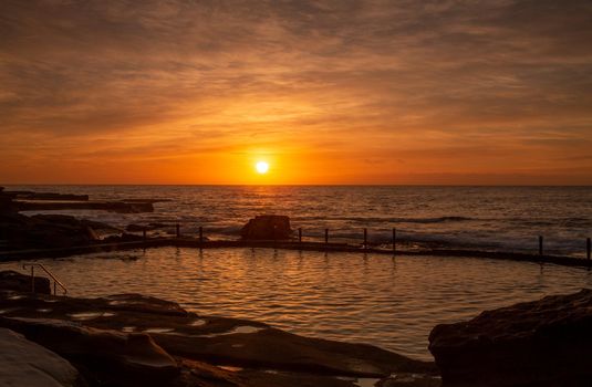 Rich orange sunrise over the ocean rock pool Maroubra in NSW Australia