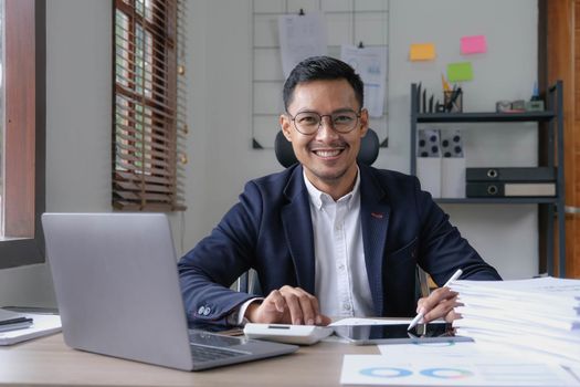 Portrait of a male business owner showing a happy smiling face as he has successfully invested his business using computers and financial