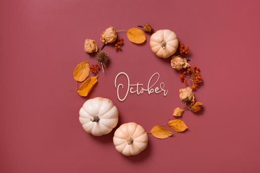 October text and autumn flat lay wreath of pumpkin, leaves and flowers with berries top view.