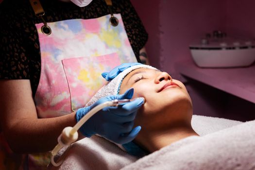 young asian woman receiving a facial treatment with an exfoliating machine, concept of beauty and wellness