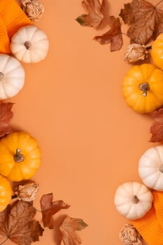 Autumn flat lay composition with pumpkins and fallen leaves and sweater with space for text. Vertical format